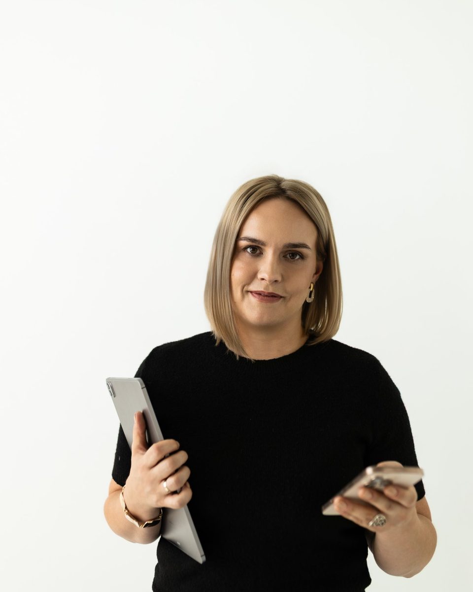 Patrycja Więckowska-Kusztelak w czarnej koszulce z tabletem i telefonem